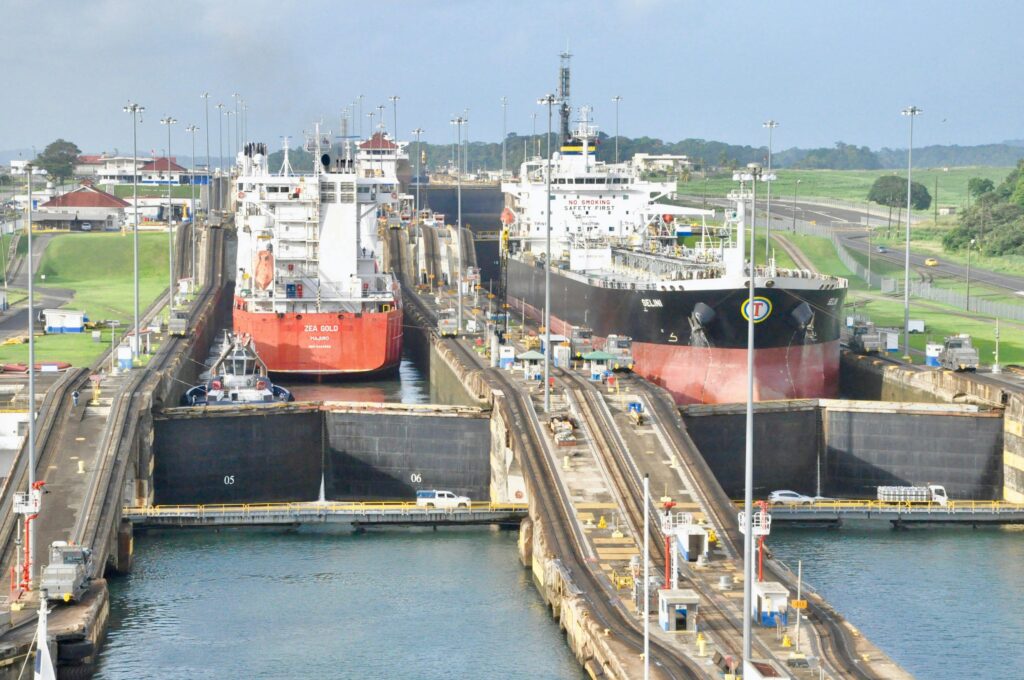 Cargo ships navigating the Panama Canal locks on a clear day, showcasing a bustling transportation hub.