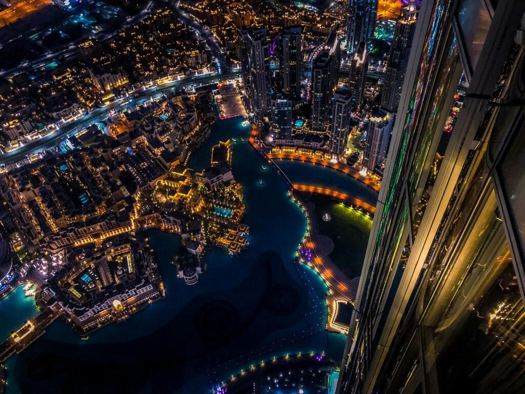 Vibrant aerial cityscape of Dubai at night with illuminated skyscrapers and urban landscape.