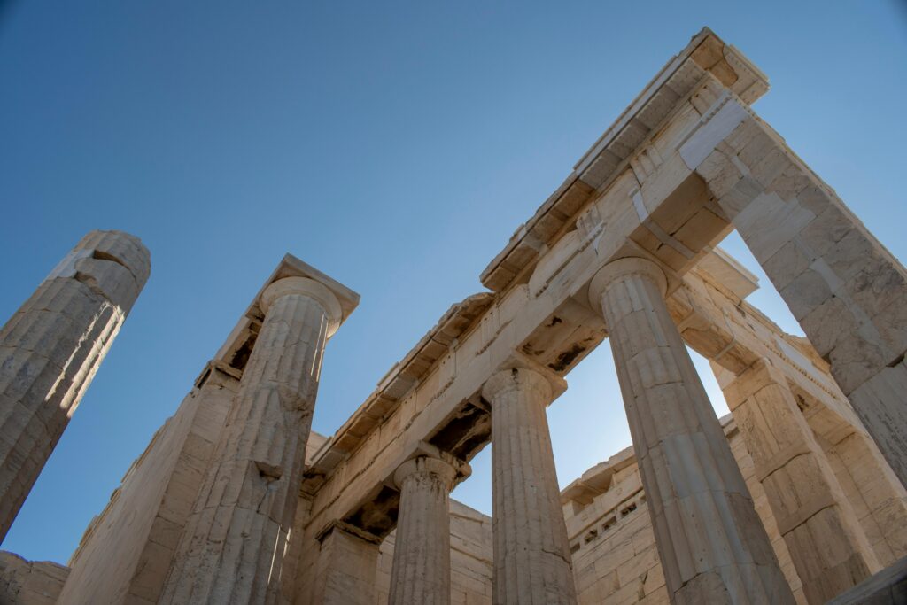 Low angle view of ancient temple ruins in Athens with clear blue sky.