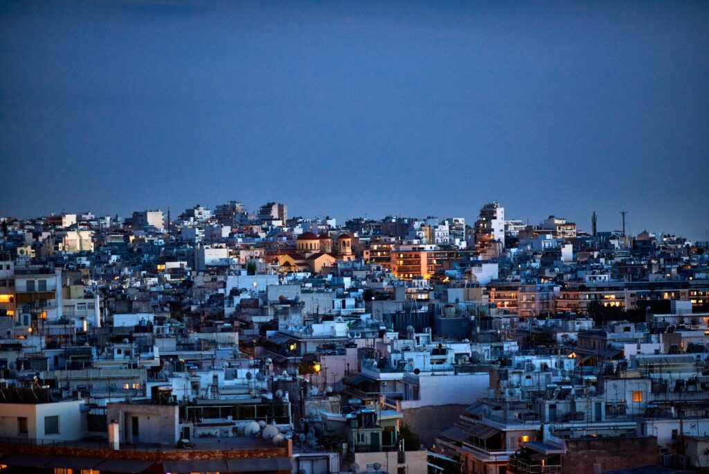 A stunning view of Athens, Greece, cityscape at dusk, showcasing illuminated buildings and a vibrant urban atmosphere.