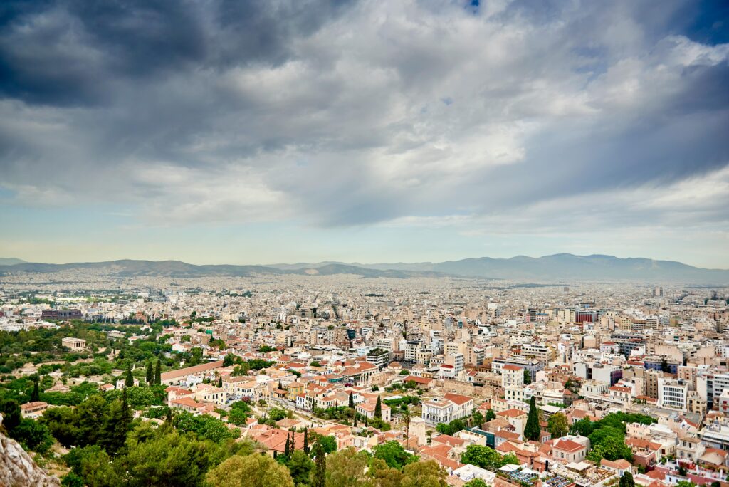 Stunning aerial view of Athens, Greece, showcasing the city's architecture under a dramatic cloudy sky.