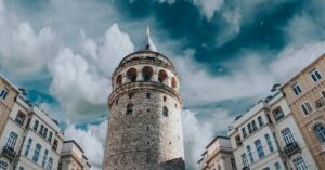 Captivating view of Galata Tower surrounded by historic architecture and dramatic clouds in Istanbul, Turkey.