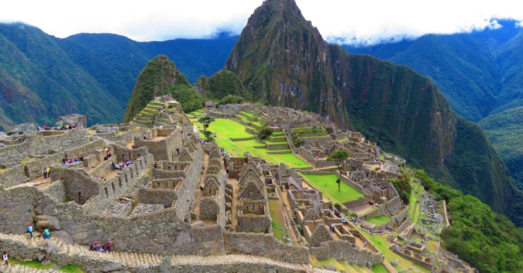 Stunning aerial perspective of Machu Picchu with lush surroundings under a cloudy sky.