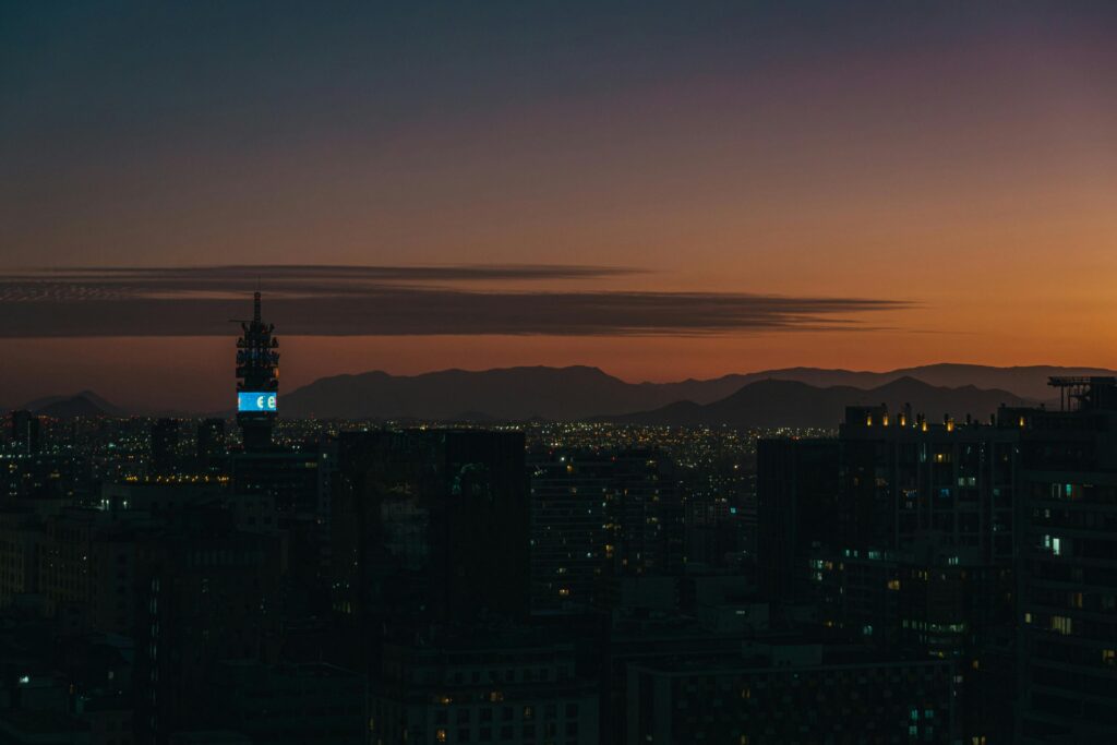 Stunning twilight view of Santiago's skyline with silhouetted skyscrapers and mountains in the horizon.