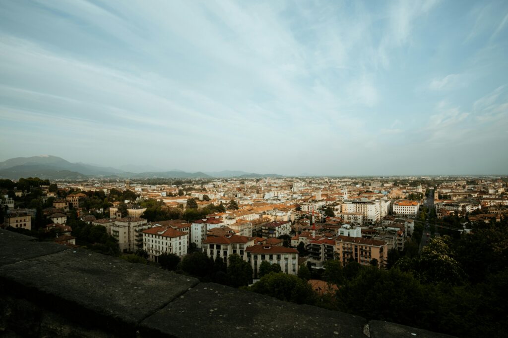A stunning aerial view of an Italian city with historic architecture and mountainous backdrop.