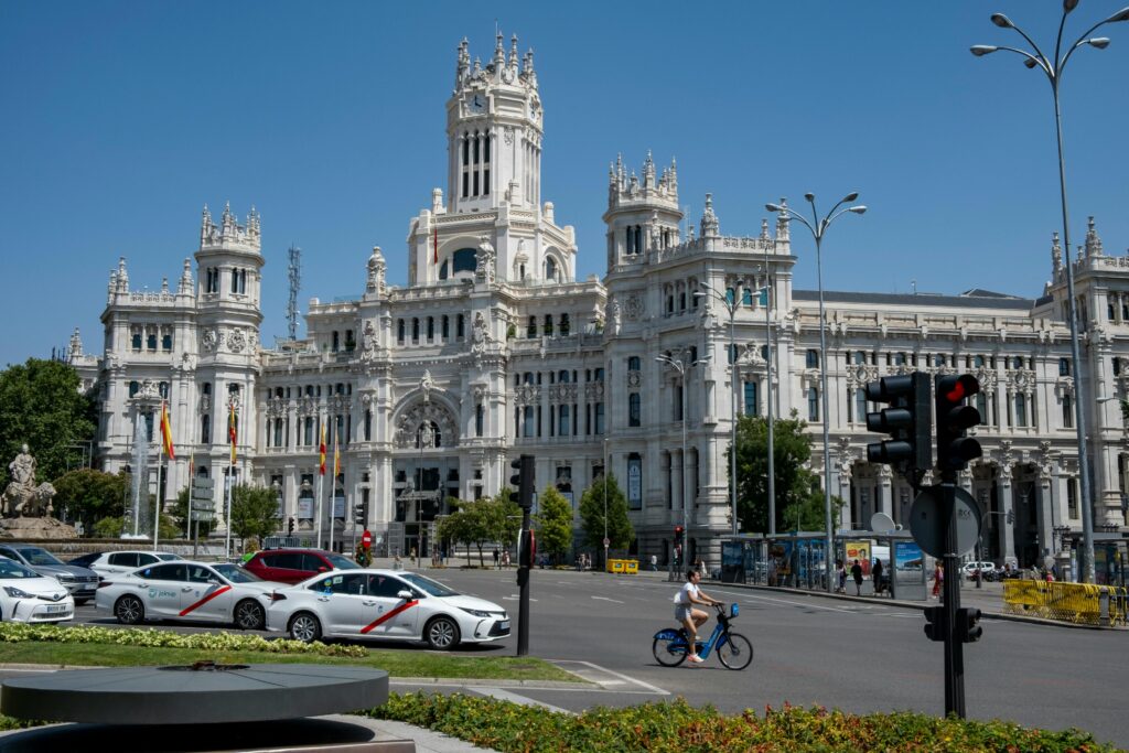 View of the iconic Palacio de Cibeles, Madrid with busy traffic and clear sky.