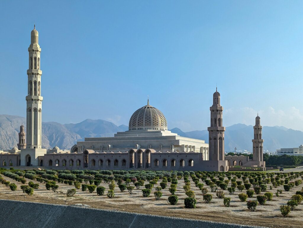 Sultan Qaboos Grand Mosque with its striking minarets against a clear blue sky in Muscat, Oman.