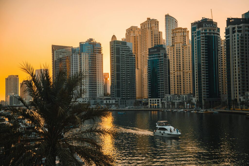 View of Dubai Marina skyscrapers with a boat on the water during a beautiful sunset.
