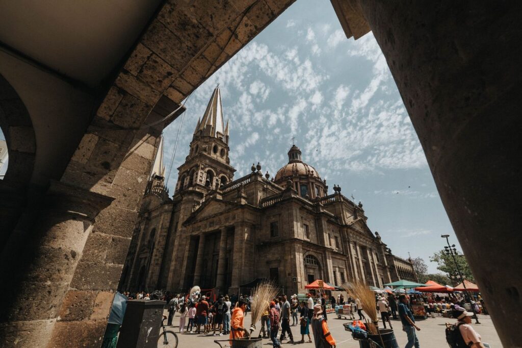 Captured under the archway, this photo showcases the stunning architecture of Guadalajara Cathedral with a lively public square.