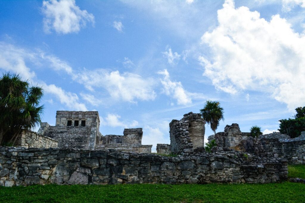 Explore the ancient Mayan ruins of Tulum, featuring historic stone structures against a vibrant sky.