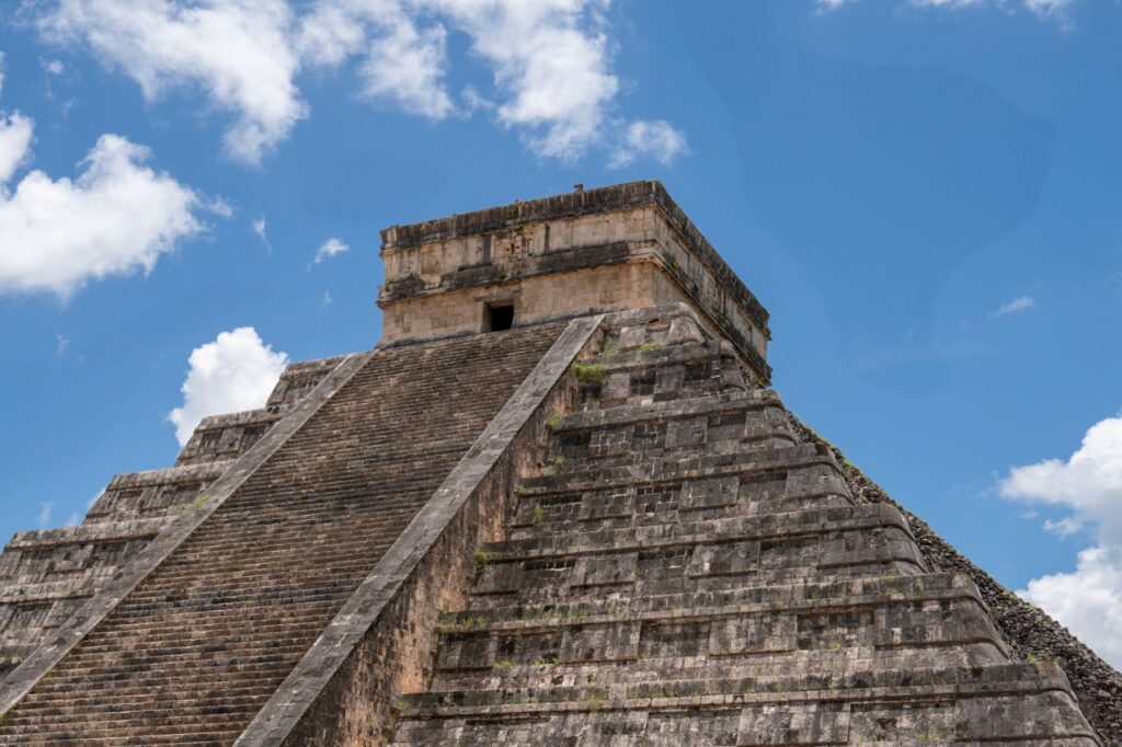 Explore the iconic stepped pyramid of Chichén Itzá against a bright blue sky.
