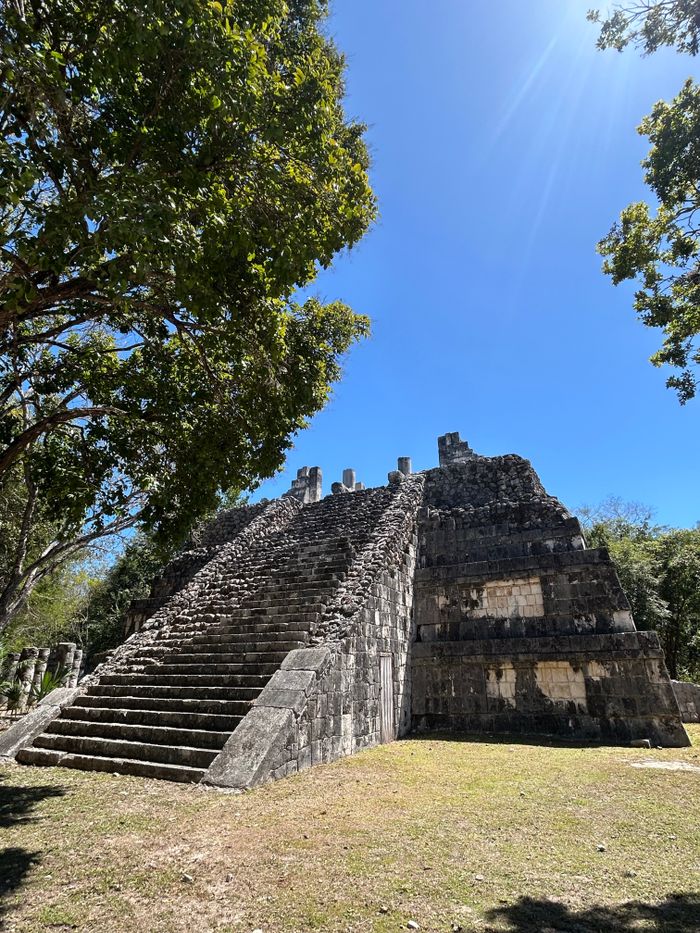 Explore the ancient Mayan pyramid surrounded by lush jungle under a bright blue sky.