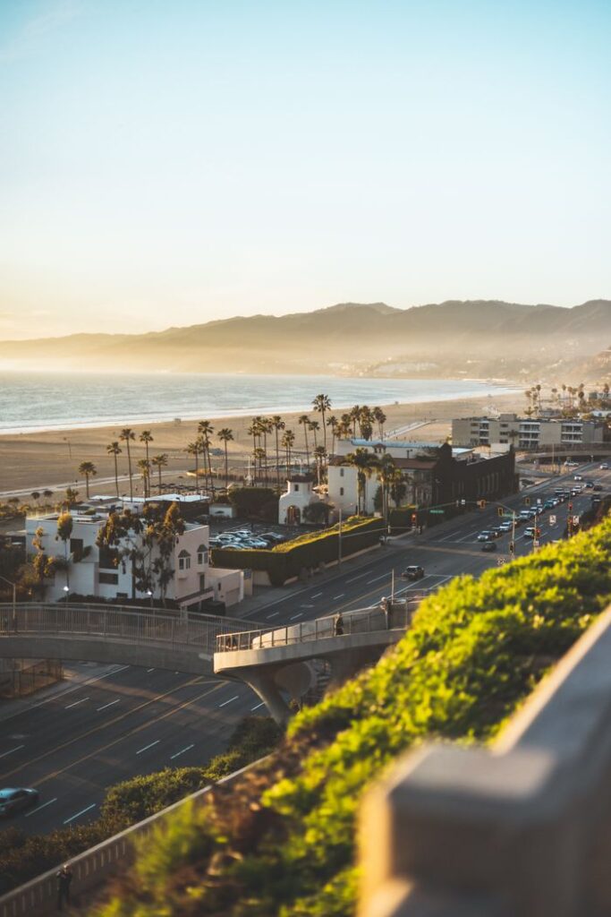 View of Santa Monica coastline with palm trees and mountains during sunset, emphasizing California's beach lifestyle.