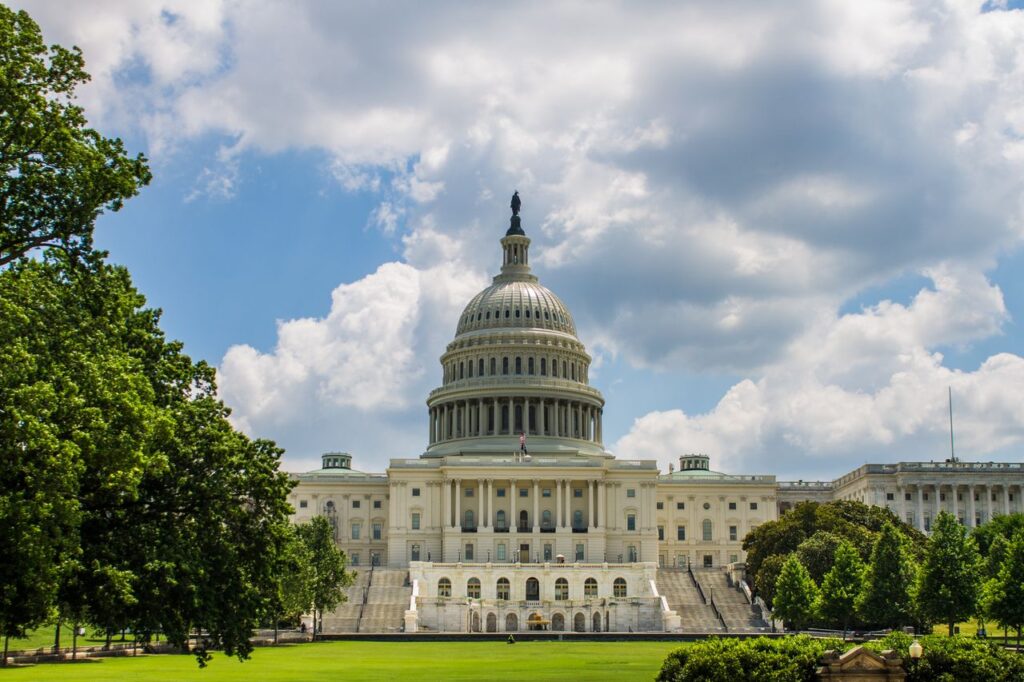Historic view of the United States Capitol under a blue sky, showcasing iconic architecture.